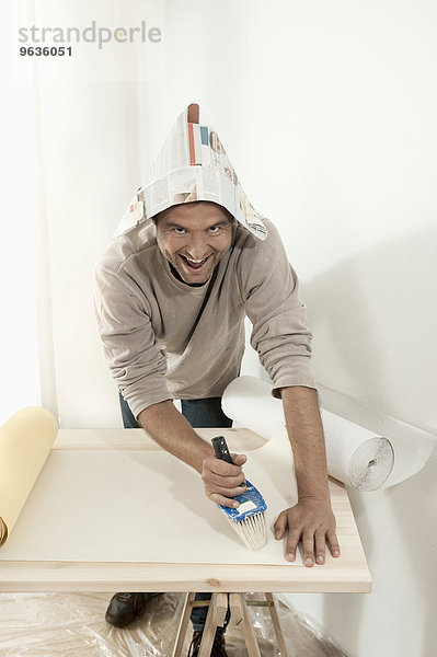 Man applying glue on wallpaper with a brush