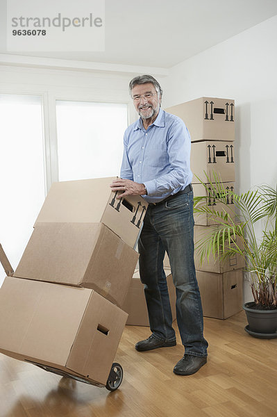 Senior man with moving boxes in new apartment