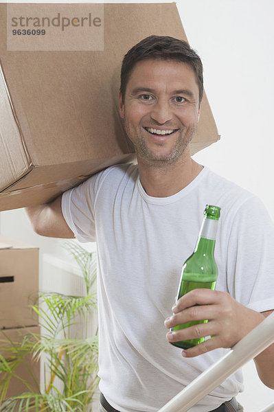 Man drinking beer while moving to his new home