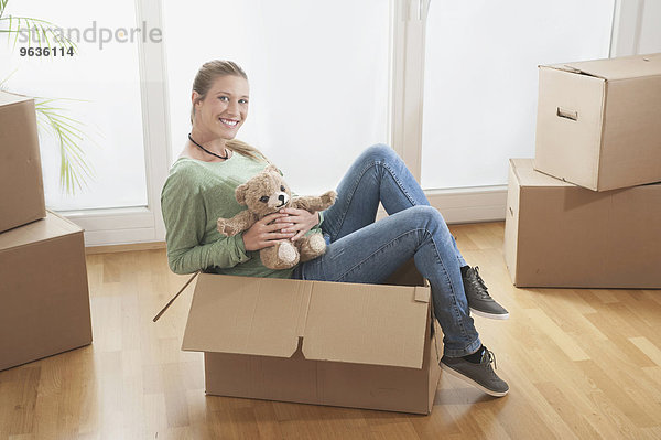 Young woman sitting in a cardboard box and smiling