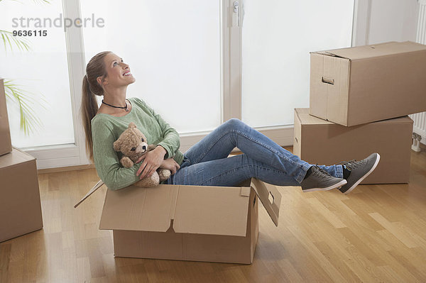 Young woman sitting in a cardboard box and dreaming about her new home