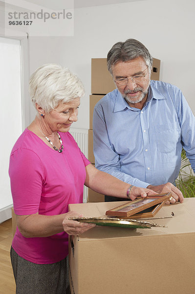 Senior couple looking at picture frames in new apartment