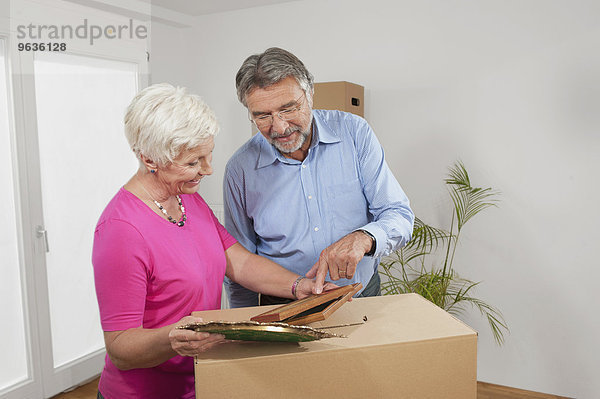 Senior couple looking at picture frames in new apartment