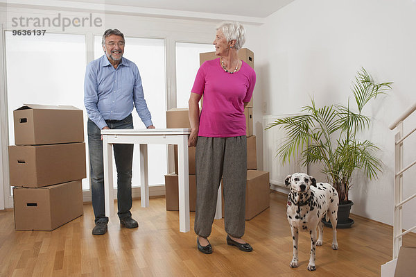 Senior couple moving a table in new apartment