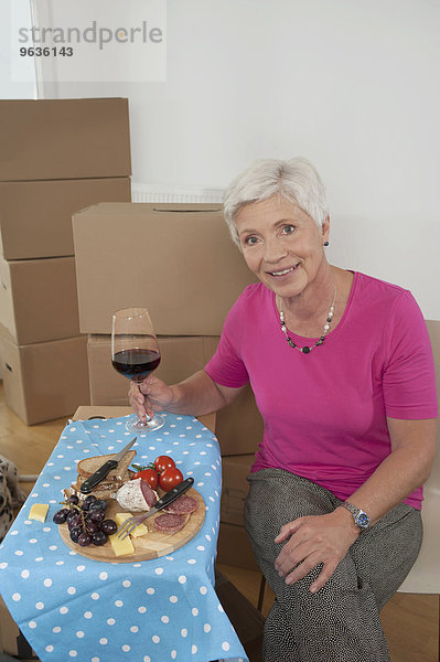 Senior woman moving into new home celebrating with wine