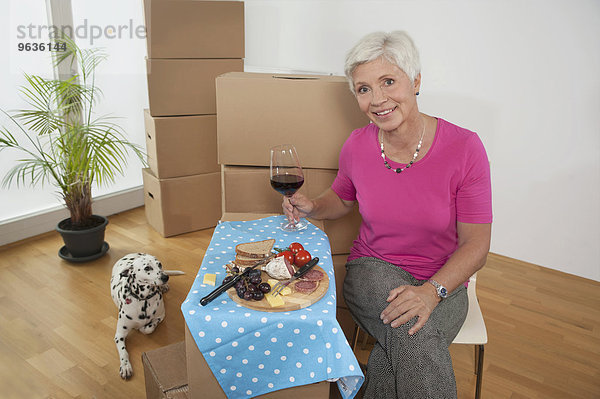 Senior woman moving into new home celebrating with wine