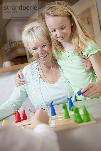 Girl playing board game with her grandmother