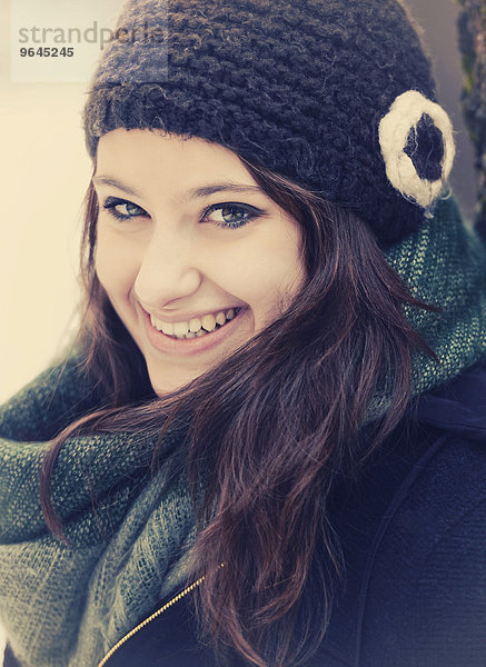 Lächelnde junge Frau mit Mütze und Schal im Winter  Portrait