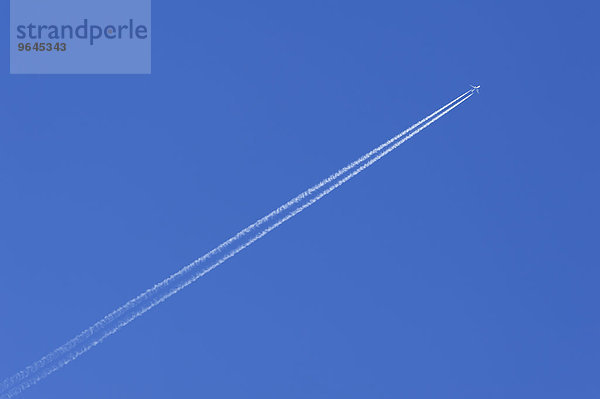 Flugzeug mit Kondensstreifen am blauen Himmel