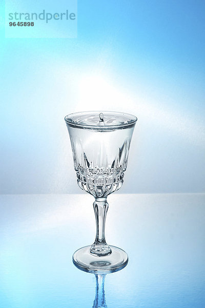 Ein Tropfen fällt in ein Glas mit Wasser