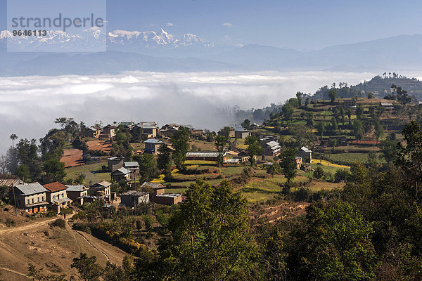 Ausblick auf Landschaft  ländliche Häuser  Terrassenfelder und Berge des Himalaya  Nebel liegt im Tal  bei Dhulikel  Nepal  Asien