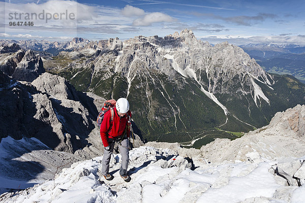 Bergsteiger beim Aufstieg über den Rotwandsteig auf die Sextner Rotwand in den Sextner Dolomiten  hier oberhalb der Rotwandwiesen  hinten die Dreischusterspitze  unten das Altsteintal  Hochpustertal  Südtirol  Trentino-Südtirol  Italien  Europa