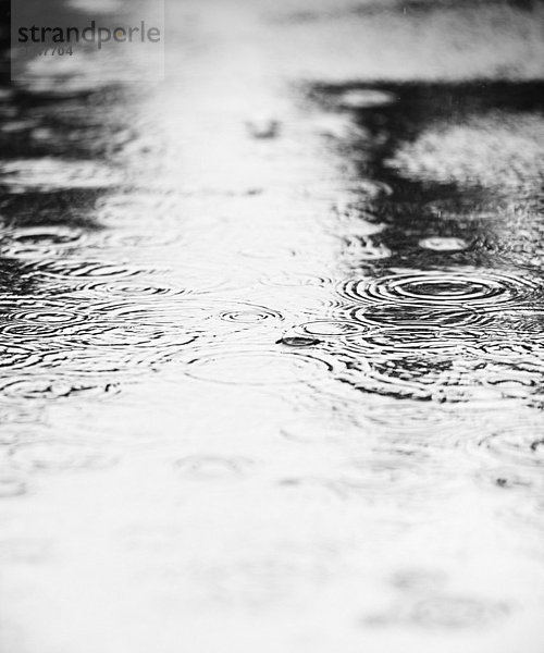 Wasserpfütze mit fallenden Regentropfen