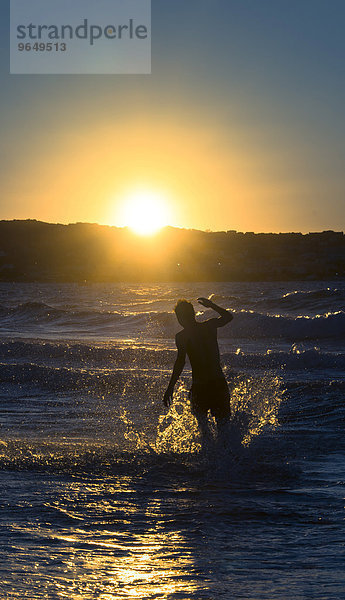 Junger Mann  Silhouette  springt im Wasser bei Sonnenuntergang  Abendrot am Meer  Haute-Corse  Korsika  Frankreich  Europa