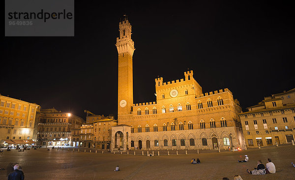 Touristen auf dem Palazzo Pubblico mit beleuchtetem Torre del Mangia und Kapelle  Nacht  Piazza Il Campo  Siena  Toskana  Italien  Europa