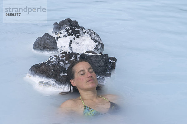 Junge Frau genießt Bad in heißer Quelle  Thermalbad  Blaue Lagune  Island  Europa