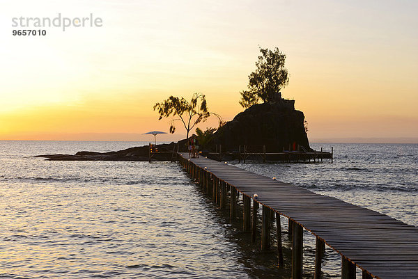 Bootssteg führt zu einer kleinen Felseninsel mit Sonnenliegen bei Sonnenuntergang  Insel Santa Maria  Madagaskar  Afrika