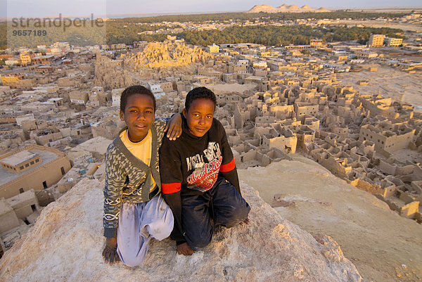 Zwei lächelnde Jungen vor der Ruinenstadt Shali  Siwa  Ägypten  Afrika