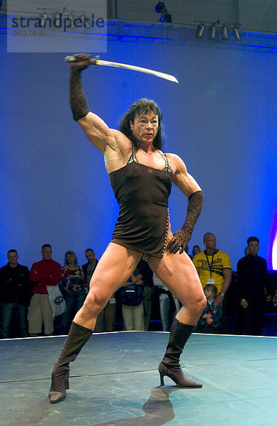 Bodybuilderin posiert mit Schwert auf der Fitnessmesse FIBO in Essen