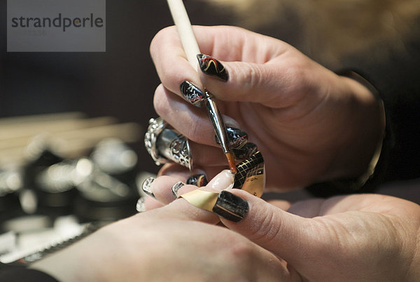 Kosmetikerin bearbeitet die Fingernägel einer Kundin in einem Nagelstudio