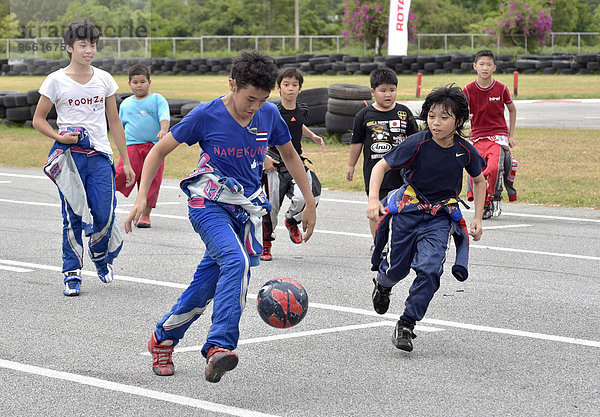 Teenager in Rennoveralls spielen Fußball  Pattaya  Thailand  Asien