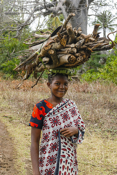 Lächelndes Mädchen trägt Brennholz auf dem Kopf  Moheli  Komoren  Afrika