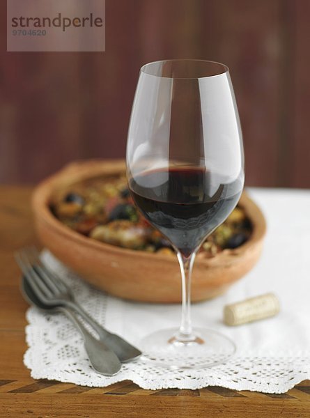 'Rotweinglas; im Hintergrund Tapas in einer Terrakottaschale'