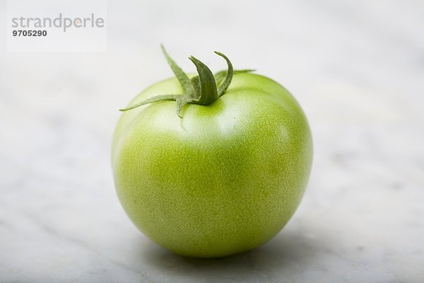 Eine grüne Tomate auf Marmorplatte