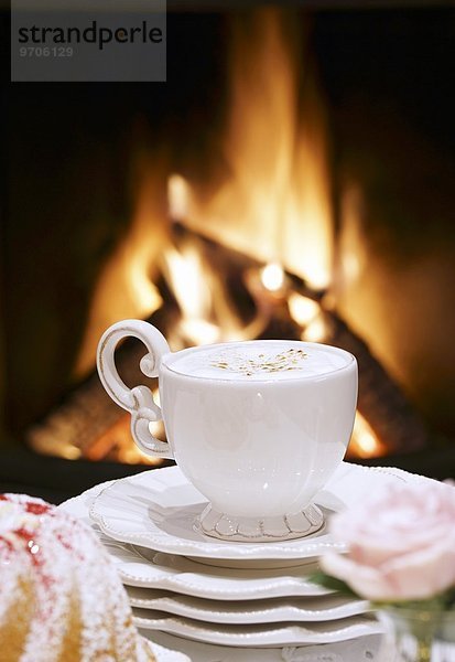 Eine Tasse Cappuccino vor dem Kaminfeuer