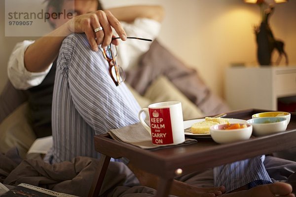 Mann isst Englisches Frühstück im Bett