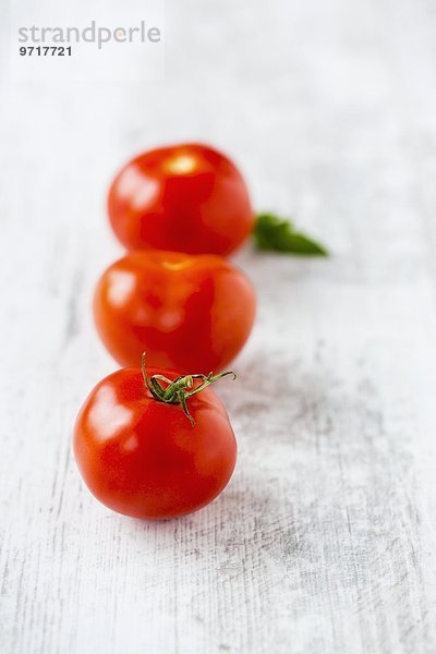 Drei Tomaten in einer Reihe mit Blatt