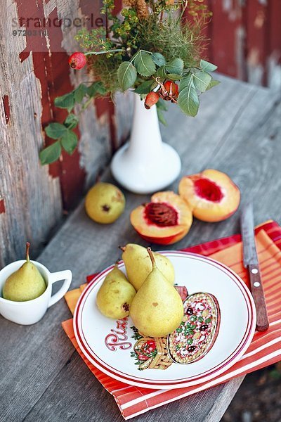 Pfirsiche und Birnen auf Holztisch im Garten