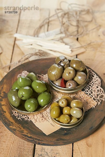 Verschieden gewürzte  grüne Oliven in drei Metalldeckel