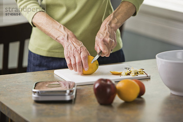 Senior Senioren Frau schneiden Frucht