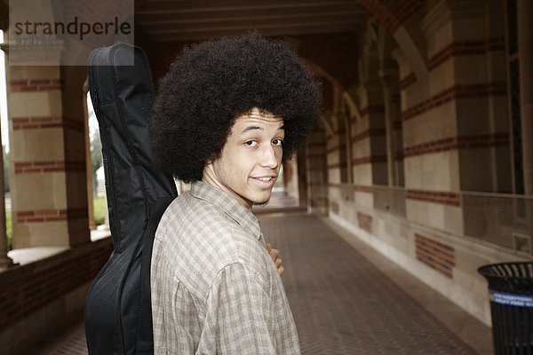 krauses Haar Afrolook Afro Afros Mann tragen Tasche Gitarre