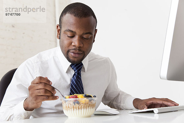 Schreibtisch Geschäftsmann schwarz essen essend isst Frühstück