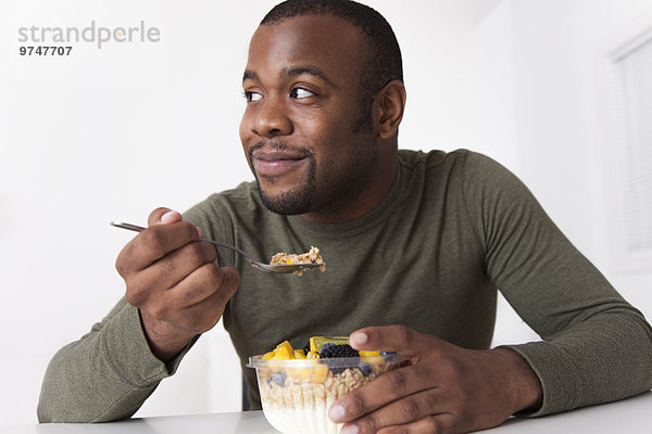 Mann lächeln schwarz essen essend isst Frühstück
