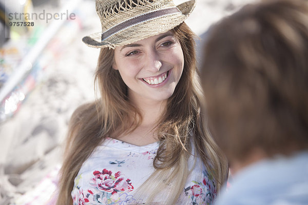 Lächelnde junge Frau schaut den Mann am Strand an.