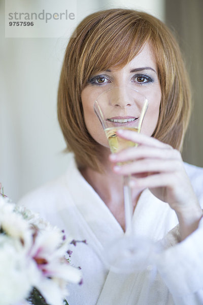Porträt einer jungen Frau  die ein Glas Champagner trinkt.