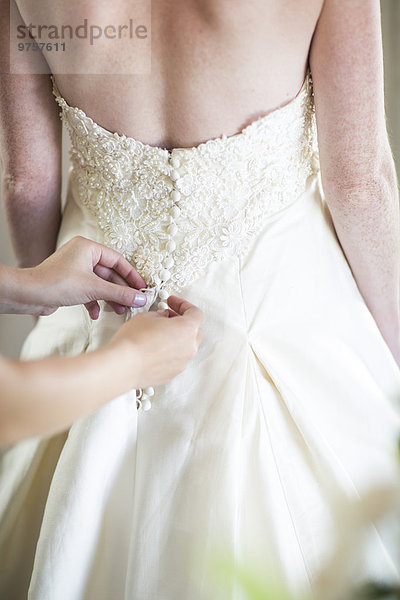 Brautjungfer  die das Brautkleid zuknöpft.