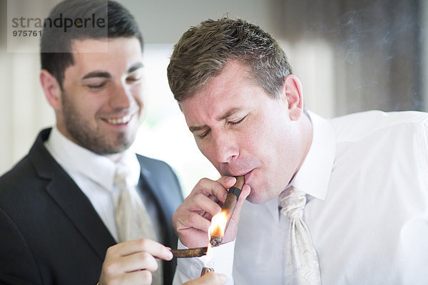 Bräutigam Rauchen einer Zigarre mit Trauzeugen vor der Hochzeit