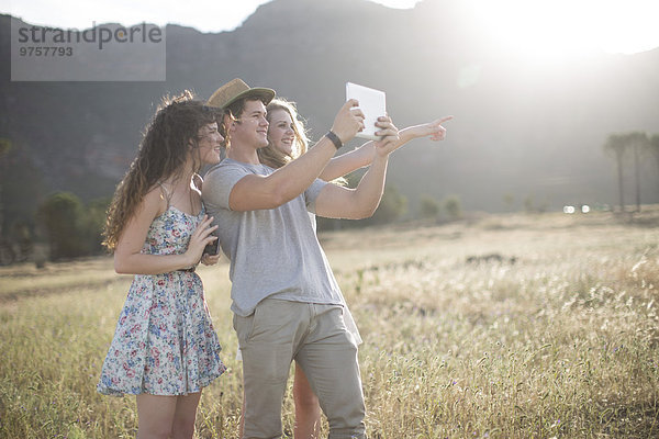 Südafrika  Freunde beim Selbstfotografieren mit Tablett im Feld