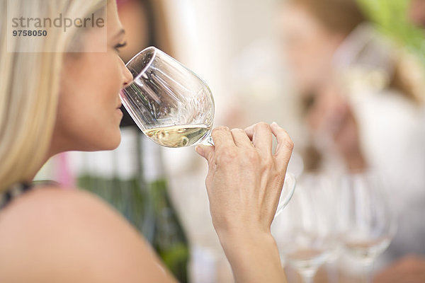 Frau riecht Weißwein bei einer Weinprobe