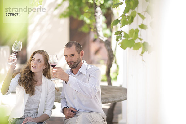 Paar im Freien sitzen und Rotwein probieren