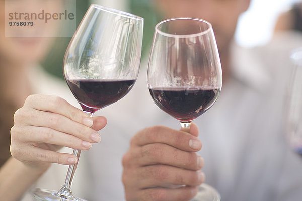 Hände halten Gläser mit Rotwein