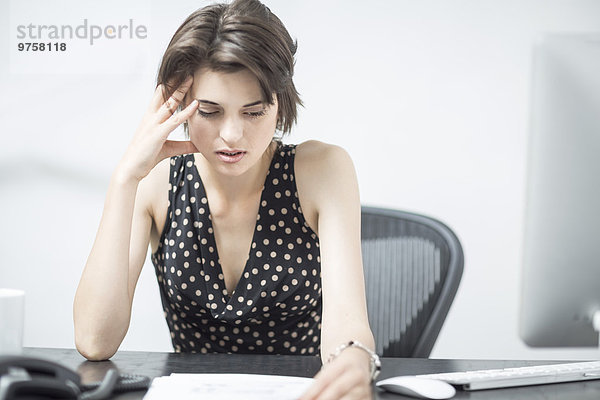 Frustrierte Geschäftsfrau am Schreibtisch sitzend