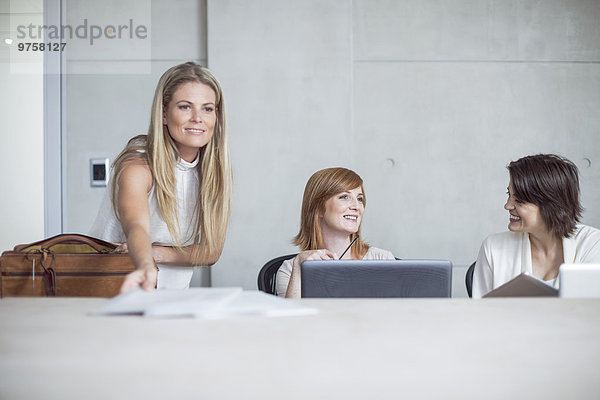 Drei Geschäftsfrauen bereiten sich auf eine Besprechung im Konferenzraum vor