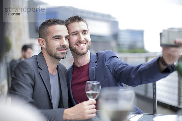 Homosexuelles Paar  das einen Selfie in einem Restaurant nimmt.