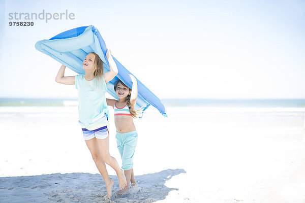 Zwei Mädchen am Strand mit einer Lilo