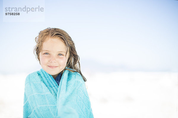 Lächelndes Mädchen am Strand in ein Handtuch gewickelt